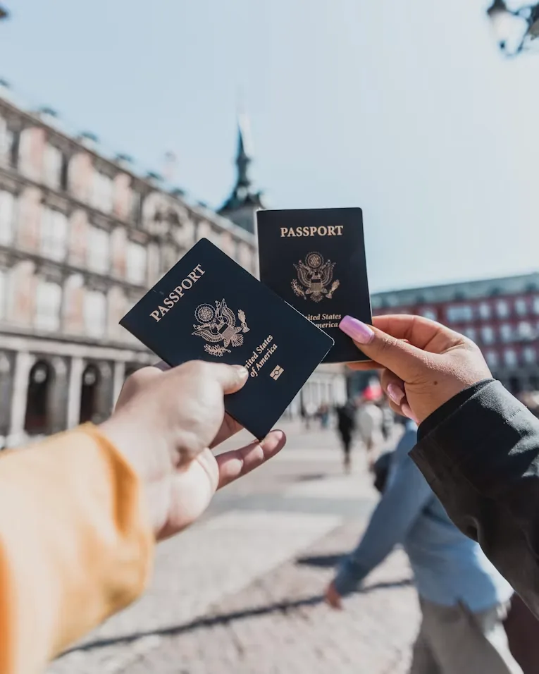 Two travellers holding up their passports in a European square