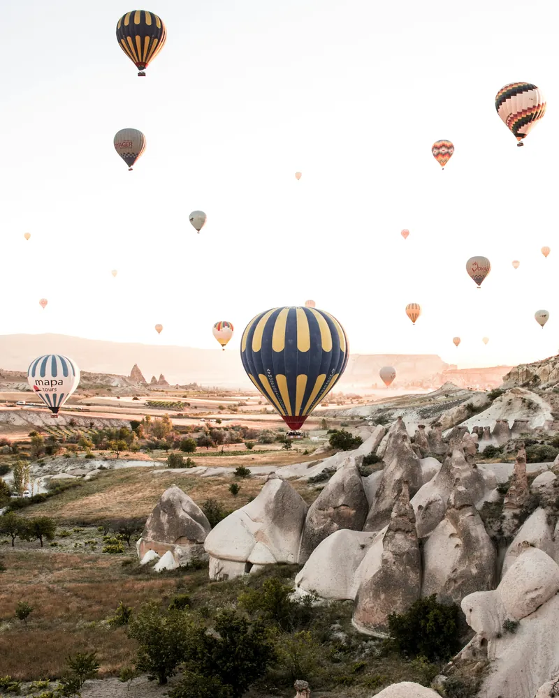Hot air balloons rising over Cappadocia at sunrise
