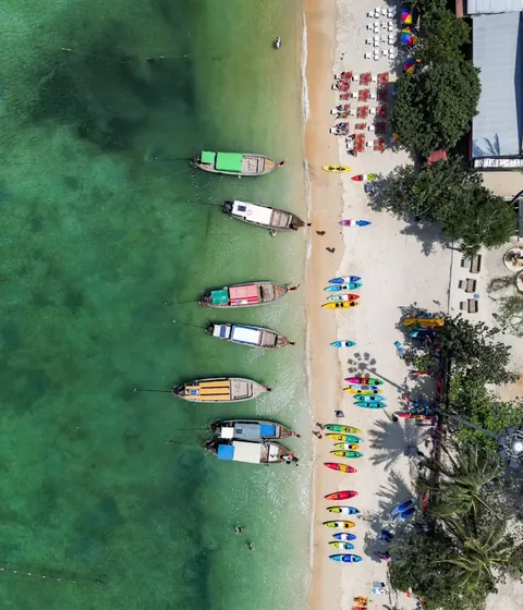 Longtail boats and kayaks on a tropical beach seen from above