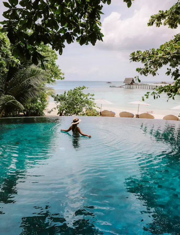Traveller in a Maldives infinity pool looking out at the lagoon and jetty