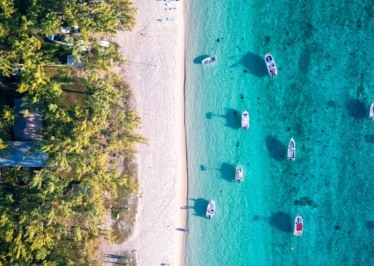Boats anchored off a white sand beach in Bali